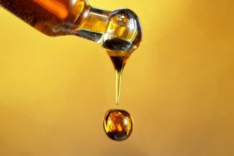 A single serving of herbal extract falling from a glass dropper