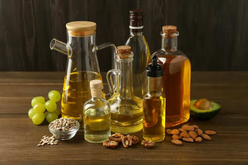 Different plant cooking oils in glass bottles with olives, flaxseed, walnuts and avocado